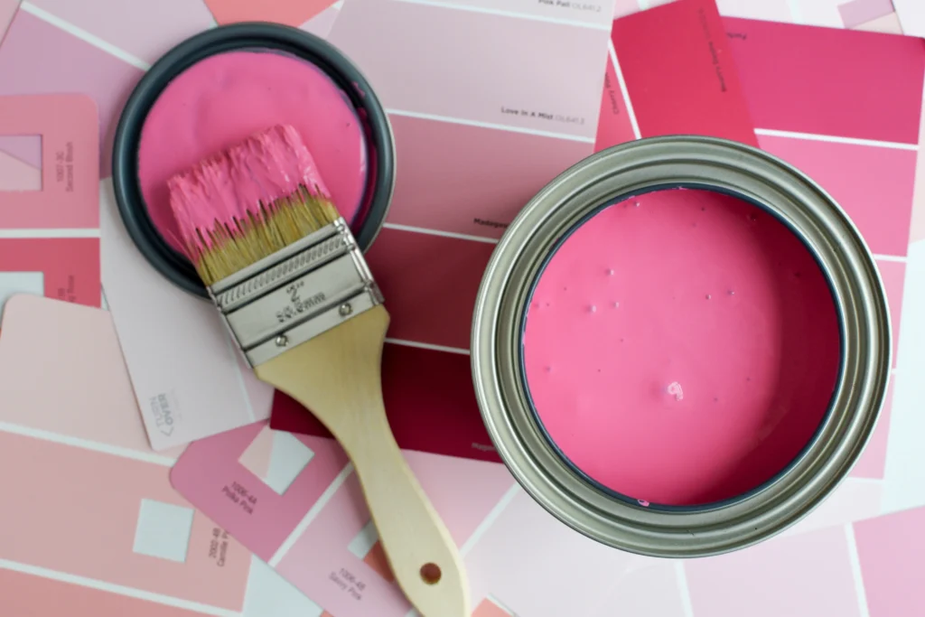 botes de pintura y brocha en tonos rosa